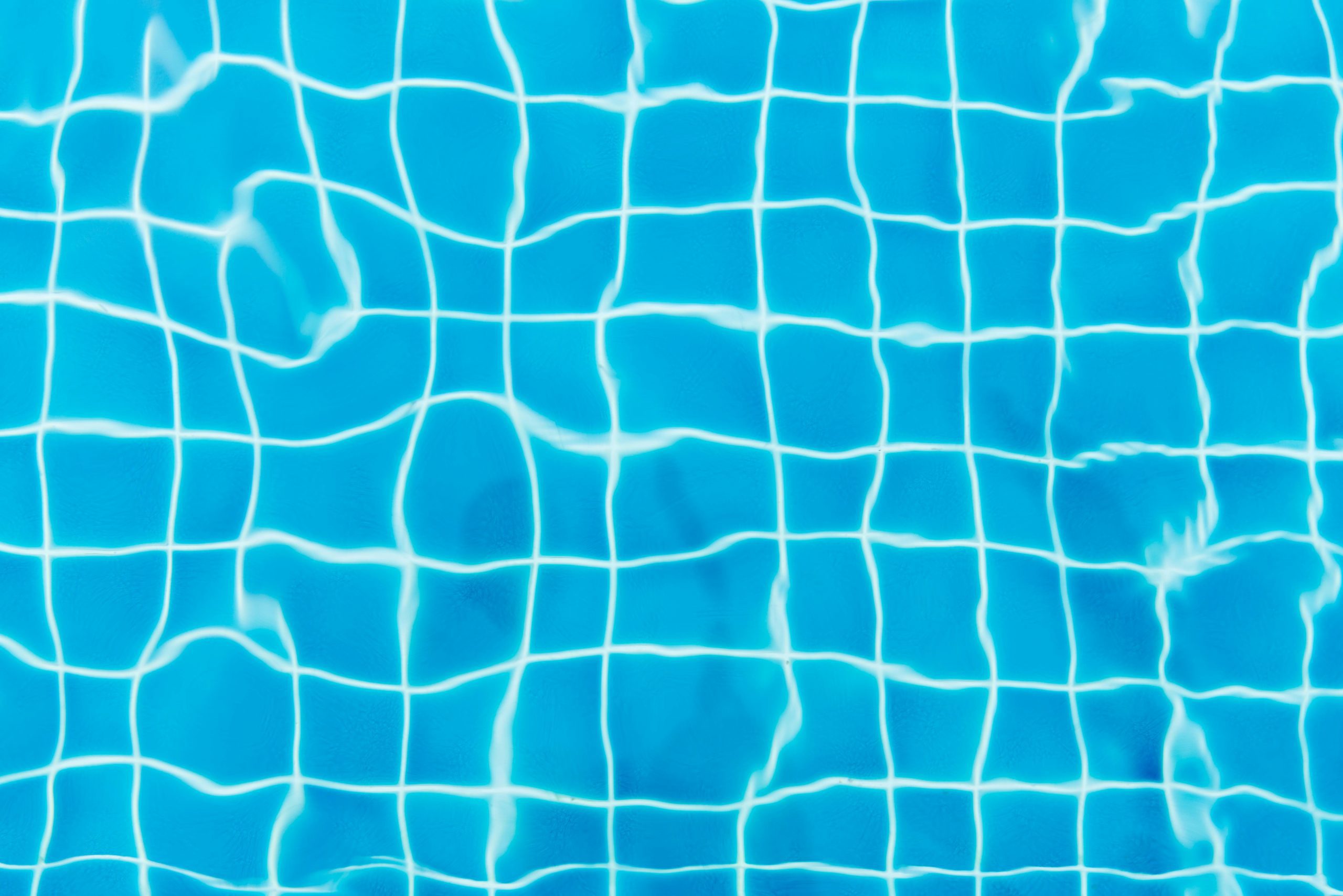 Top view of a swimming pool with vibrant blue water and tile patterns.